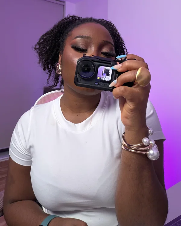 Omobolaji wearing white and holding a camera