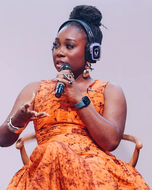 Omobolaji wearing orange and speaking into a microphone